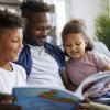 dad reading book to two children 