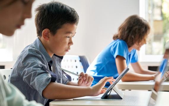 Child sitting at a desk in a classroom using a table for school work