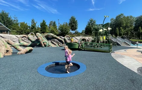 Girls jump on a trampoline feature at the inclusive Inspiration Playground at Bellevue Downtown Park things to do with kids in Seattle